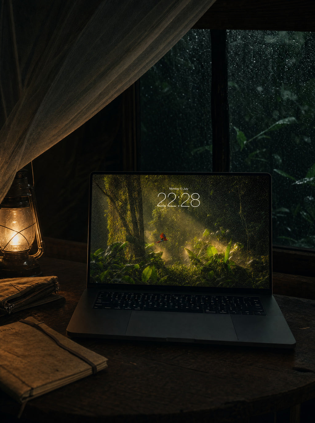 Canopy Rain wallpaper on a MacBook Pro at a jungle-lodge desk under a mosquito net