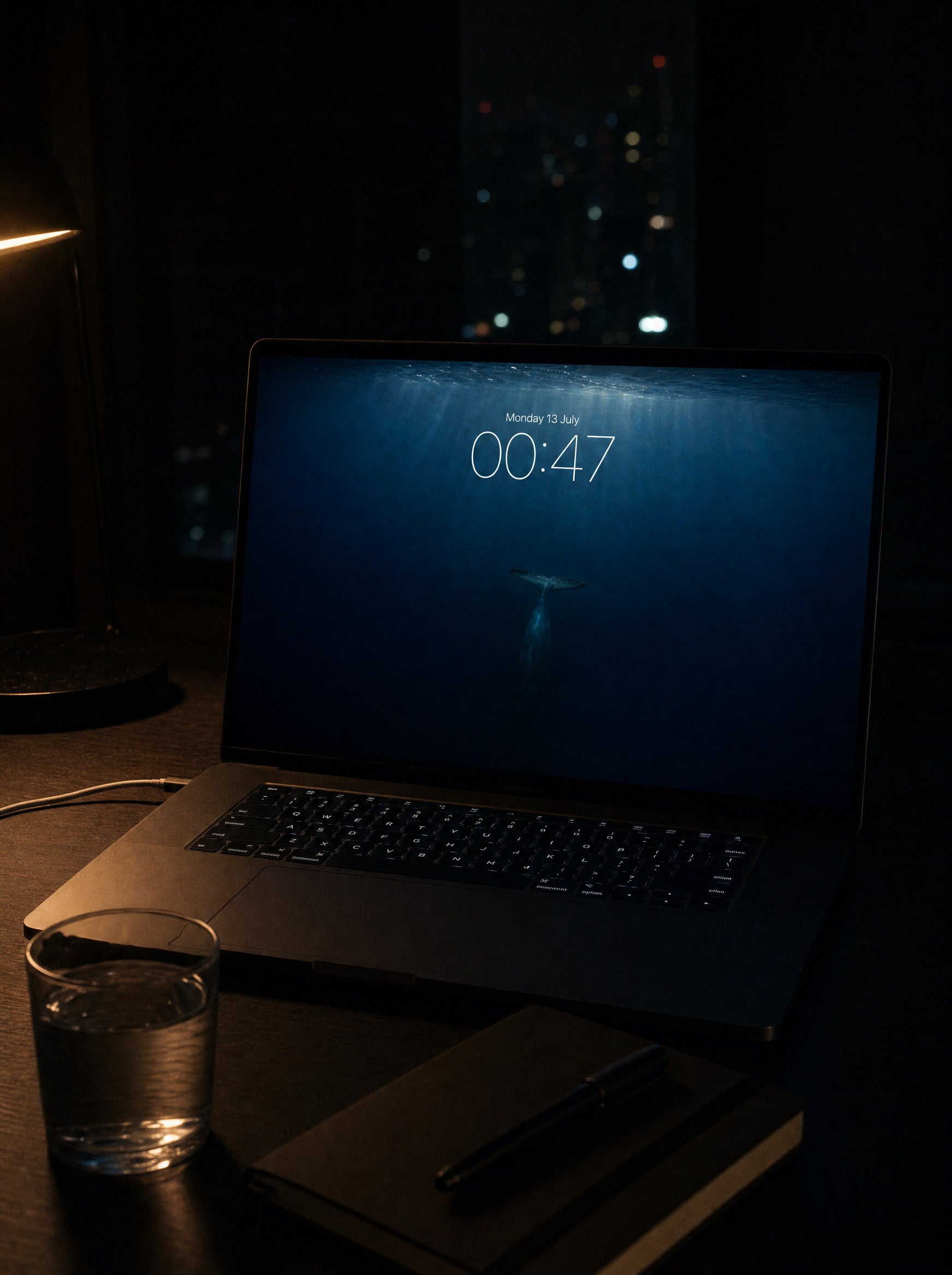 The Long Dive wallpaper on a MacBook Pro at a midnight desk